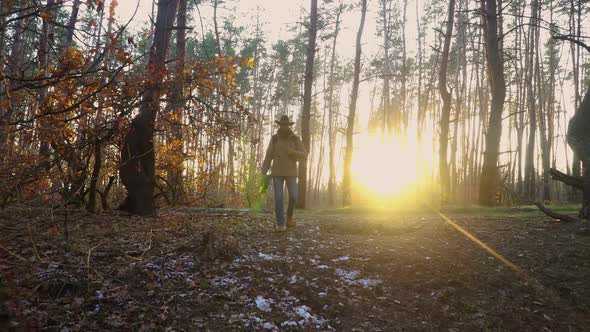 A Backpacker with a Guitar and a Camera Walks Along in the Forest