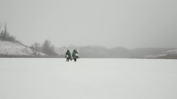 Winter fishing. Two men are going through frozen lake for winter fishing