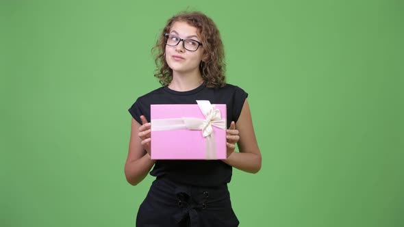 Young Beautiful Nerd Woman Thinking While Holding Gift Box