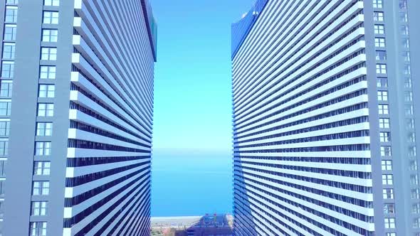 the drone flies between two buildings with glass windows.