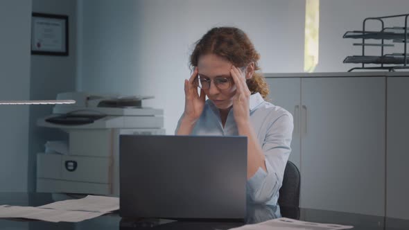 Portrait of Tired Young Businesswoman Using Laptop Computer at Office Desk