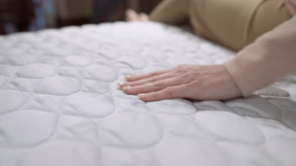 Female Hand Stroking Caressing White Soft Duvet on Bed Indoors