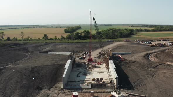 Crawler cranes erected on rural countryside construction site, building infrastructure. Aerial rotat