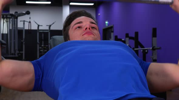 A Young Fit Man Does Inclined Bench Press in a Gym - Closeup