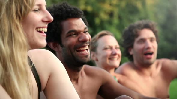 Four friends laughing while sitting in nature