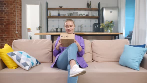 Millennial Woman Opening Cardboard Box with Order