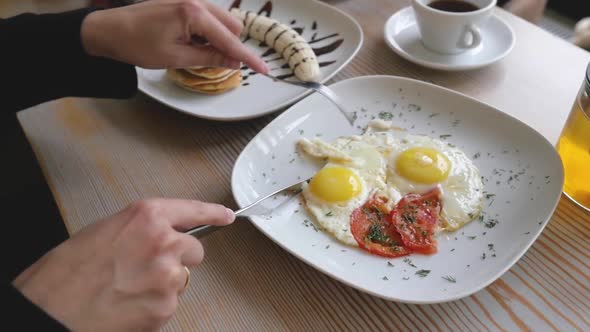 Female Hands Close-up with Fork and Knife Over Scrambled Eggs. Woman Having Breakfast, Close Up