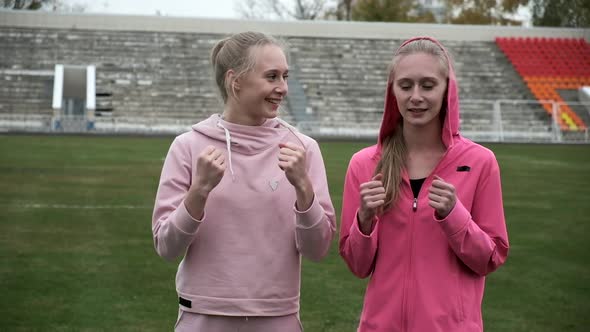 Young Fit Sporty Caucasian Pretty Twin Sisters Boxing Outdoors at Stadium Field