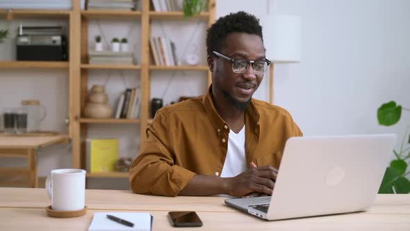 Man Talking in Video Chat and Sitting at Table with Laptop at Home Interior Spbas