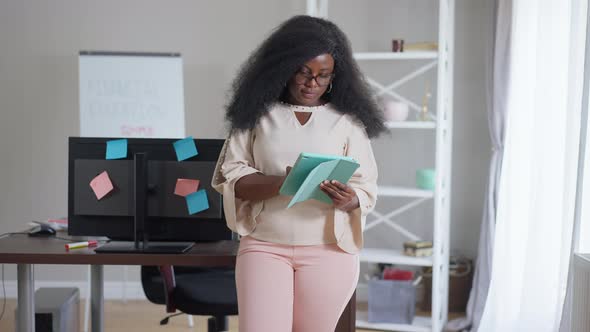 Young African American Female CEO Surfing Internet on Tablet Standing in Office Indoors