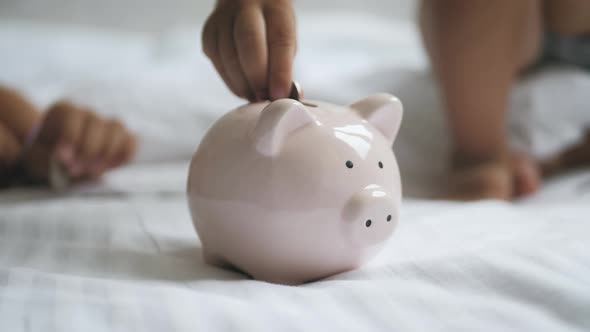 Children Save Money in Piggy Bank in Her Home. Kid Inserting a Coin Into a Piggy Bank, Indoor