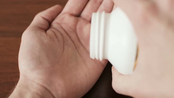 Hands of a Man Pouring Fish Oil Capsules to Hand Closeup