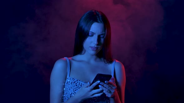 Portrait of Charming Young Woman Views Content on Her Phone Then Shows Smartphone with a Green