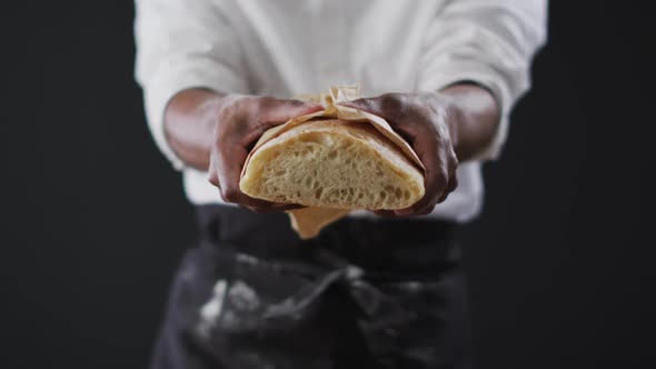 Video of cook holding loaf of bread on black background