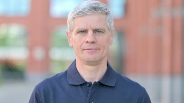 Outdoor Portrait of Serious Middle Aged Man Looking at Camera