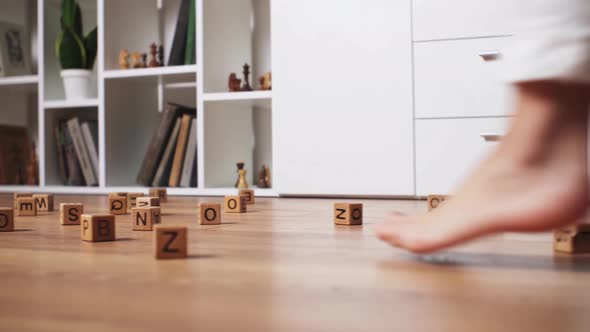 Close Up Legs Walk Along The Floor Bypassing The Scattered Cubes With Letters Women's Feet