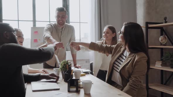 Businesspeople Putting Their Fists on Top of Each Other on the Desktop in Nice Light Workstation