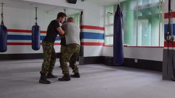 Two caucasian men learning self defense from trainer in gym