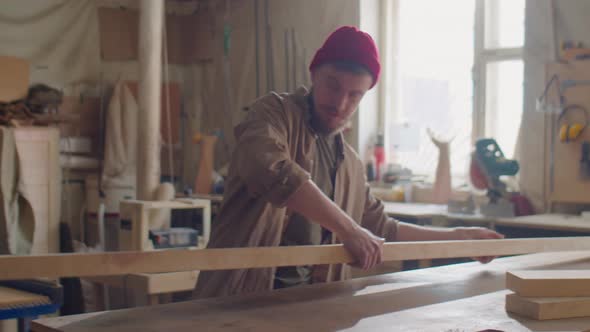 Woodworker Putting Plank on Workbench