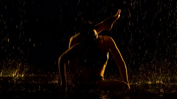 Exercise the Leg Behind the Head. Young Woman Practices Yoga Asanas in a Dark Studio in the Rain