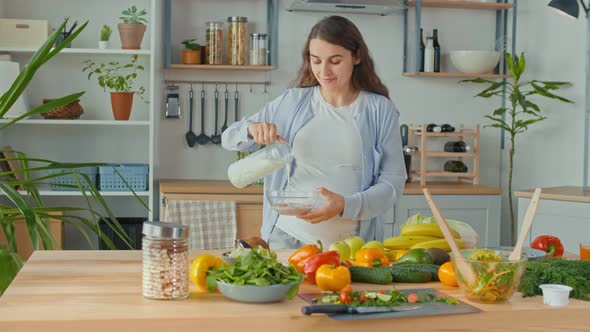 Happy Pregnant Woman Preparing a Bowl of Healthy Breakfast With Milk and Muesli