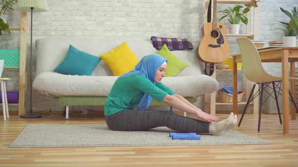 Sporty Muslim Woman in Hijab Doing Warmup in a Modern Apartment