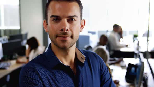 Male executive standing with arms crossed in office 4k