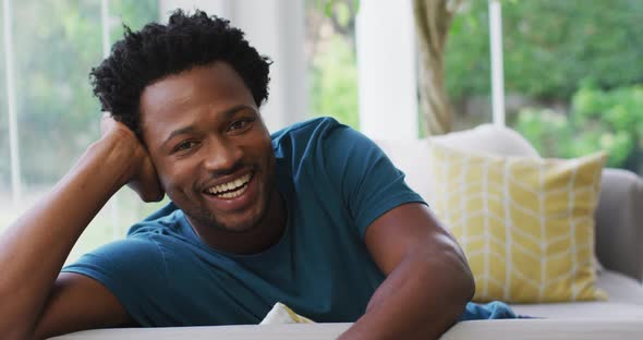 Portrait of biracial man sitting on sofa and smiling to camera