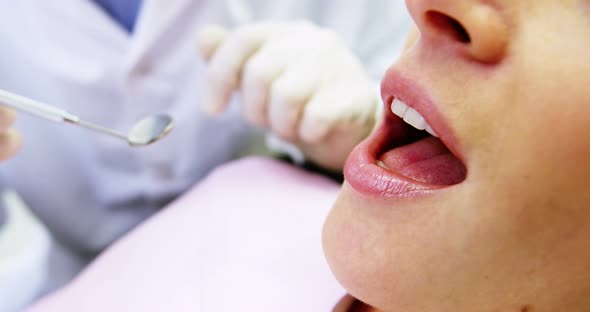 Dentist examining a female patient with tools