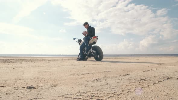Man Motorcyclist with Bike on a Dry Salt Lake