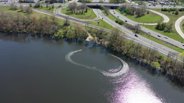 An aerial view of a lake during the day. On the lake there is a gas powered, remote controlled speed