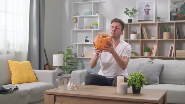 Man Examines a Pumpkin Before Carving Jack's Lantern