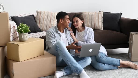 Happy Married Couple in Love Man and Woman of Different Nationalities Sit on the Floor Between Boxes