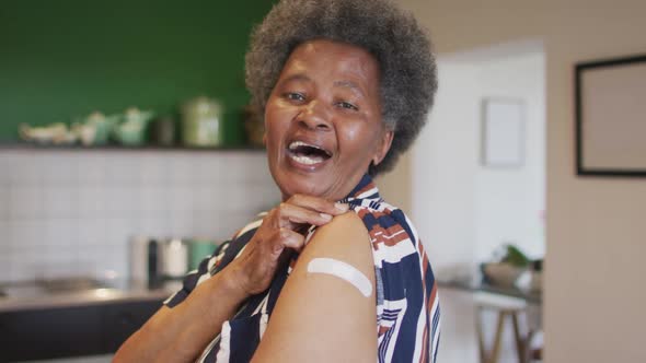 Happy senior african american senior woman showing plaster on arm after covid vaccination