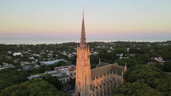 Aerial parallax shot orbiting around San Isidro Cathedral spire at sunset in Buenos Aires