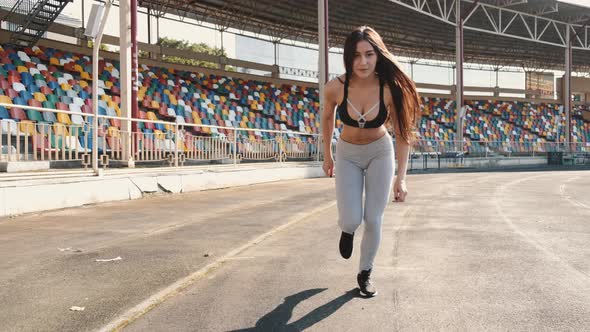 Beautiful Young Woman Starts Running at Sports Stadium