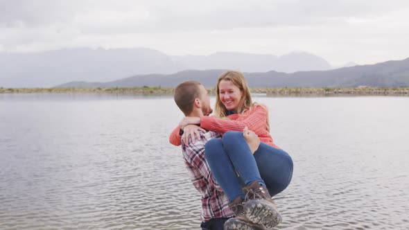 Caucasian couple having a good time on a trip to the mountains, smiling, the man holding the woman