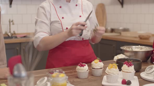 Female Cook Showing Ways of Cupcakes Decoration