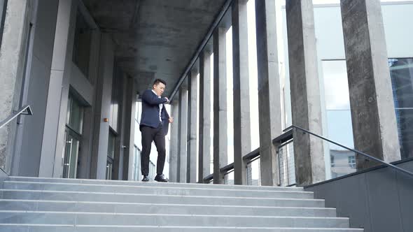 Cheerful happy asian business man dancing walk the stairs backdrop a modern office