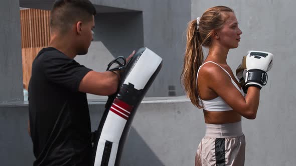 Young Woman in White Top Having a Boxing Training with Her Coach Outside Kicking the Portative