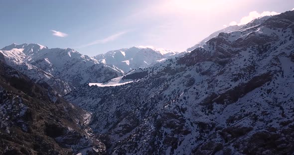 fly over an snow covered valley with a rural road to village. Persian Juniper trees visible in beaut