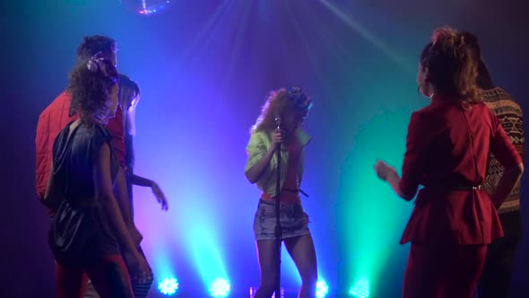 Girl Performing on Stage As Audience Dances in Smoke Studio. Smoke Background