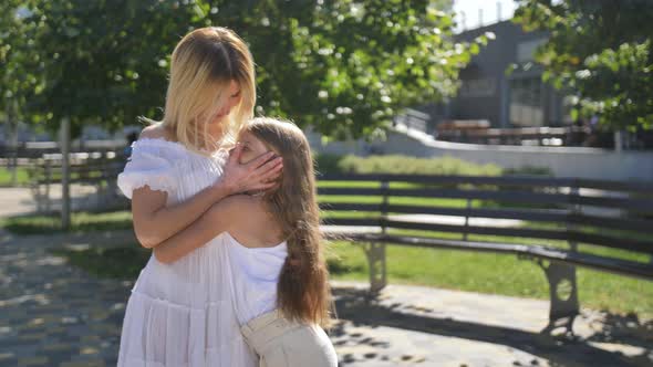 Loving Mom and Daughter Hugging Kissing Outdoors