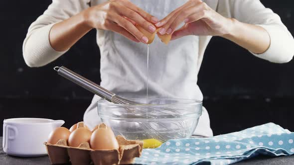 Woman breaking eggs into a bowl