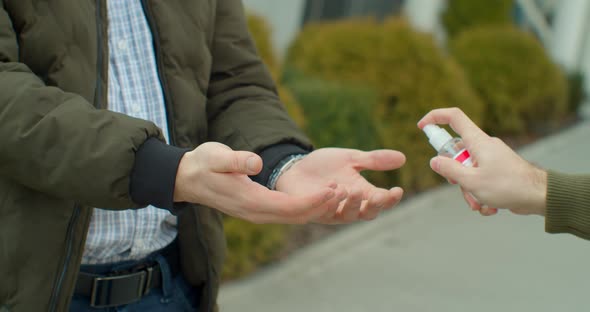 Man Wearing Disposable Medical Face Mask Makes Disinfection of Hands with Sanitizer. Epidemic of