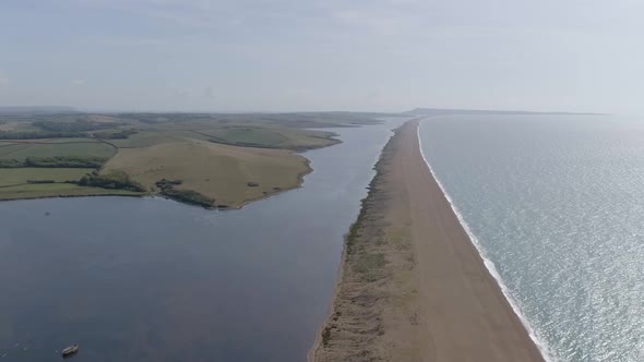 Aerial tracking along the grand barrier that is Chesil Beach on the Dorset coast. Shot looking east