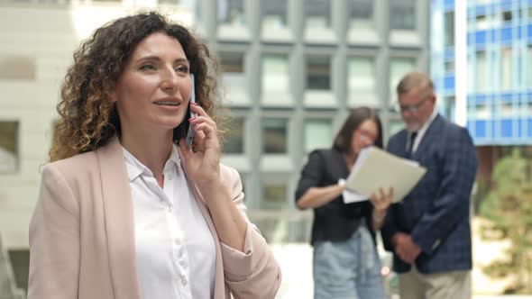 Portrait of a Middleaged Businesswoman Talking on a Mobile Phone in the Courtyard of a Large