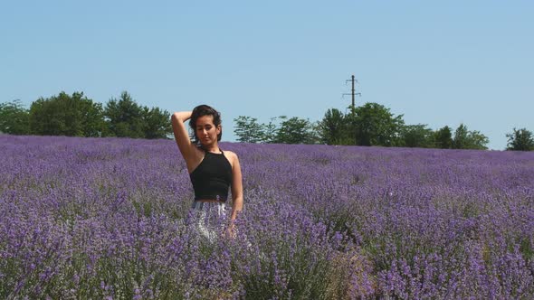 Beautiful woman is sitting in a lavender field. Lavender scent of beautiful flowers.