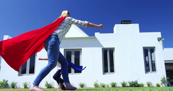 Mother and son in superhero costume having fun in garden 4k