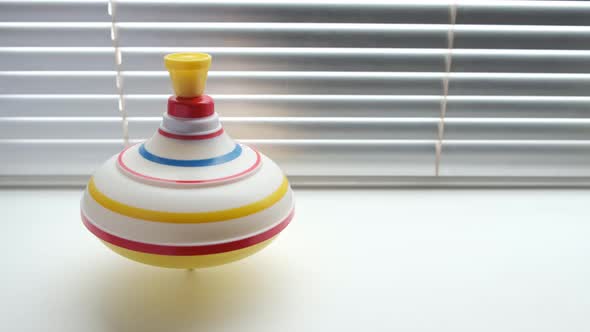 Spinning whirligig, child toy on background of blinds.